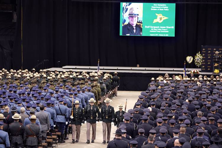 FILE - A likeness of New Hampshire State Police Staff Sgt. Jesse Sherrill appears on a screen, top, during a Celebration of Life service for Sherrill at the SNHU Arena, Nov. 3, 2021, in Manchester, N.H. A Connecticut truck driver who was charged in a highway crash that killed the New Hampshire state trooper has changed his plea to guilty. The crash killed Sherrill in fall 2021. Jay Medeiros of Ashford, Connecticut, was later charged with negligent homicide and reckless conduct. (AP...