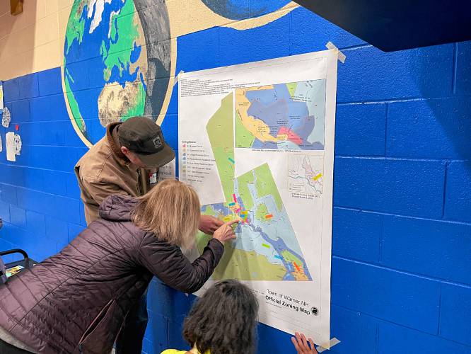 Bret Ingold, left, places a sticky note on Warner's zoning map, indicating where he thinks new housing should be added to town. 