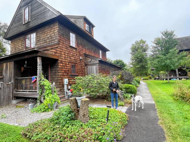 Sue Chollet, the first resident of the Nubanusit Neighborhood, stands in front of the four-bedroom house she moved into in 2007, with her new rescue dog, Rosie.