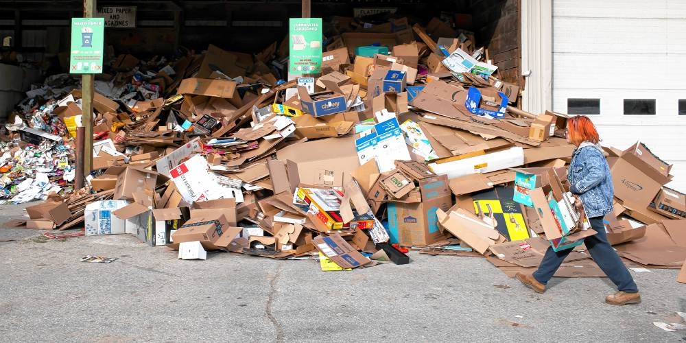 Sarah Kelley of Hopkinton walks up with cardboard boxes at the recycling pile at the Hopkinton Webster Transfer Station in Hopkinton on Wednesday, January 3, 2024.