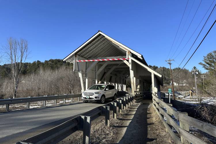 A vehicle passes through the Miller's Run covered bridge in Lyndon, Vt., on Tuesday, March 12, 2024. The historic bridge is under threat from truck drivers relying on GPS meant for cars continually hitting the bridge. (AP Photo/Lisa Rathke)