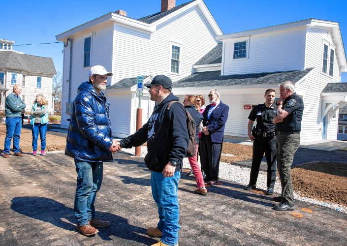 Larry Regan (left) greets David Lee Josselyn and Connor Spern at the grand opening at the Pleasant Street complex on Tuesday. Josselyn and Regan have apartments now.