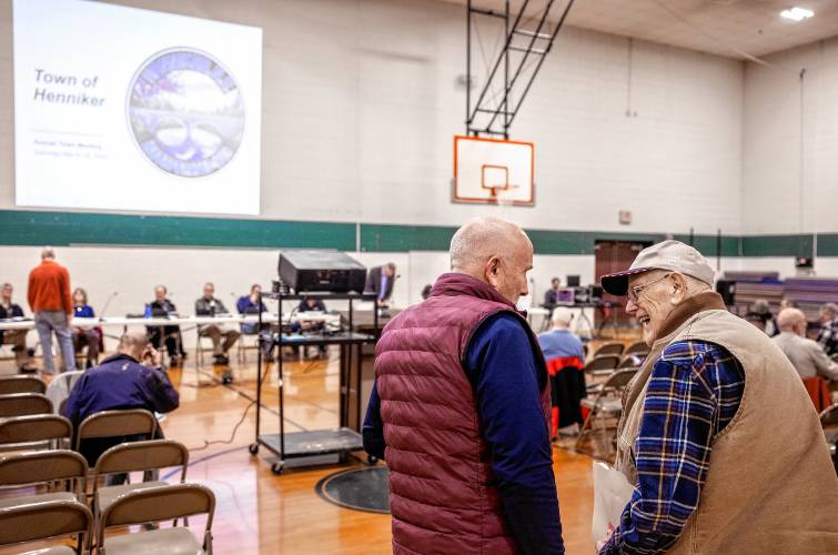 Henniker school board member Matt Center (left) talks with former selectman Leon Parker before the start of the town meeting on Saturday.