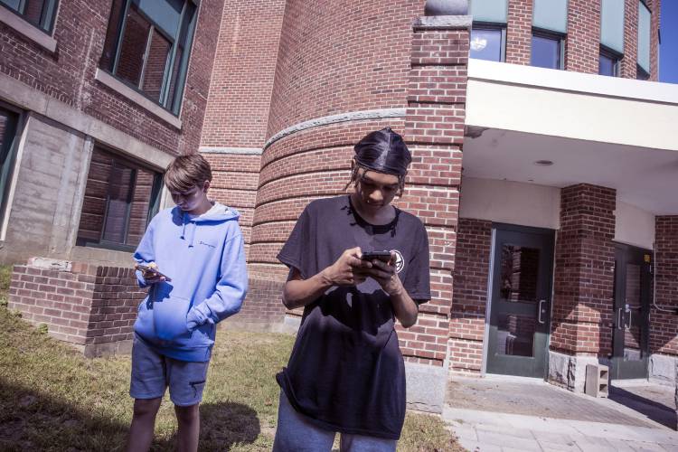 Concord High students Davison Lyford, left, and Shawn Duntley look on their cell phones during German class held outside on Thursday. Their teacher allowed them to use their phones during class period as they were looking up words.