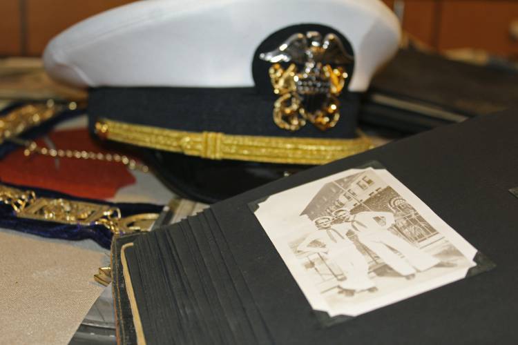 A white U.S. Navy cap, Navy memorabilia and old photographs are displayed on the kitchen table of Pearl Harbor survivor Ira 