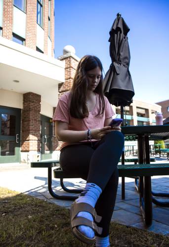 Concord High freshman Magnolia Boulton sits in front of the school on her cell phone during her German class on Thursday, September 12, 2024. Her teacher allowed the students to look on their phones during class.