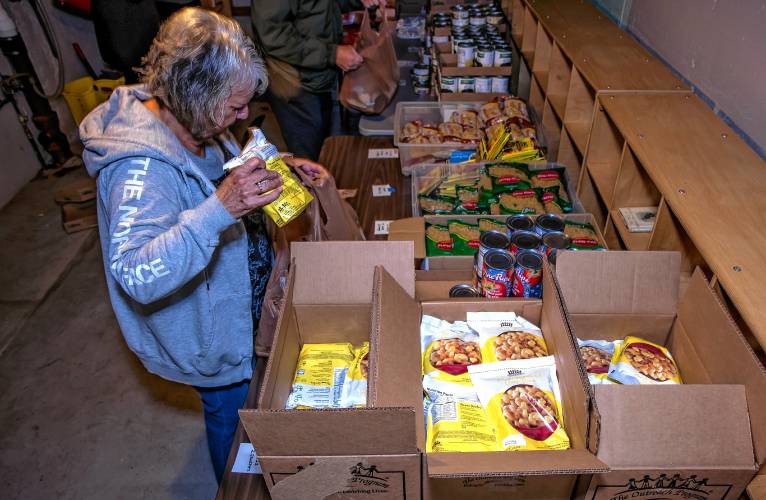 Volunteer Darlene Batza fills food into bags for distribution at the food bank located in the basement of the Early Head Start building in Pittsfield on Thursday, September 26, 2024.