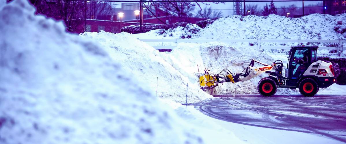 A front loader with a plow from Outdoor Pride pushes the snow from the latest snow storm into piles at the Dartmouth Health parking lot at sunrise on Thursday, February 13, 2025. Another bigger storm is due this weekend.
