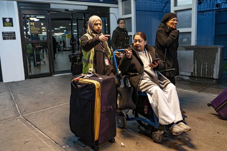 An airline passenger speaks with a wheelchair attendant outside a terminal at LaGuardia Airport in New York, Tuesday, Nov. 21, 2023. (AP Photo/Peter K. Afriyie)