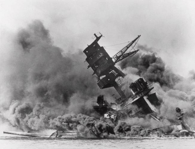 FILE - The battleship USS Arizona belches smoke as it topples over during a Japanese surprise attack on Pearl Harbor, Hawaii, on Dec. 7, 1941. The Navy and the National Park Service will host a remembrance ceremony Thursday, Dec. 7, 2023, marking the 82nd anniversary of the attack on Pearl Harbor that launched the U.S. into World War II. (AP Photo/File)
