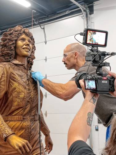 Benjamin Victor works on the sculptiure of Christa McAuliffe in his workspace.