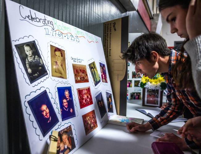 Jayson and Sierra Lessard look over the photo board celebrating their stepfather Rodney Moody at his service at Centerpoint Church in Concord on March 30.
