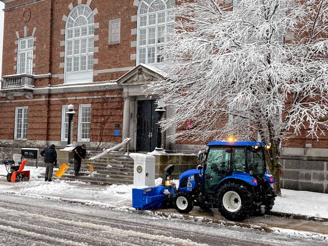 Crews clear ice and slush from the front of Concord City Hall Thursday morning. The storm knocked out power to thousands around the state and was expected to remain a wintery mix through Friday.