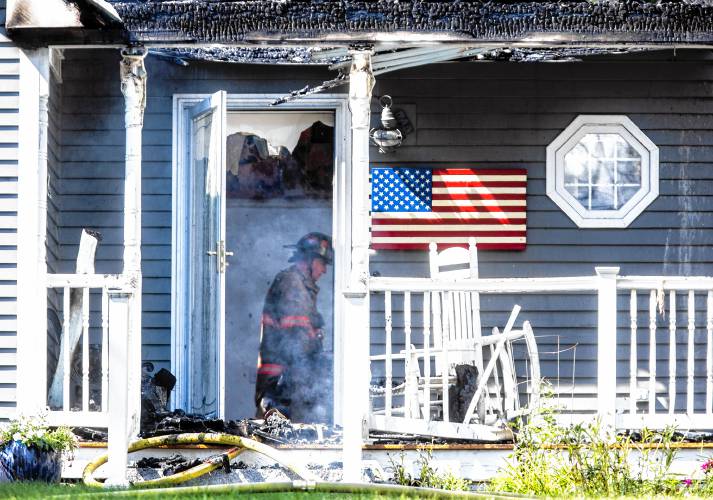 A firefighter sits in the entrance of the house on Elm Street in Concord after a fire gutted the middle of the dwelling on Saturday afternoon, July 13, 2024.