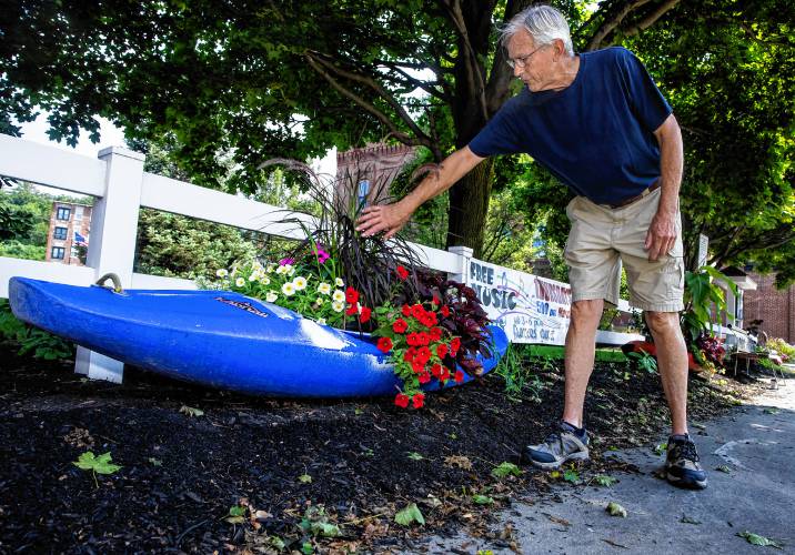 Glenn Morrill stands along Central Street in Franklin, where kayaks adorn the street repurposed as flower beds. Morrill leads a team of volunteers behind the kayak flowerbeds each year.