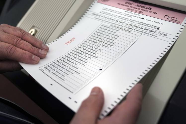 Nick Zaharias of Derry, N.H., a public witness, loads a test ballot into a vote counting machine while testing machines before the New Hampshire primary on Tuesday, Jan. 16.