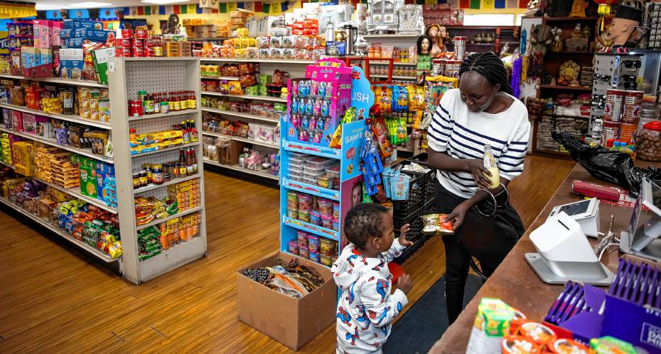 Awili Ozalla gives her son his treat as she checks out her food items at the Katmandu Bazaar Market on Loudon Road in Concord.