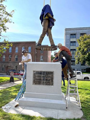 Workers put the statue of Christa McAuliffe into place at the State House before the unveiling.