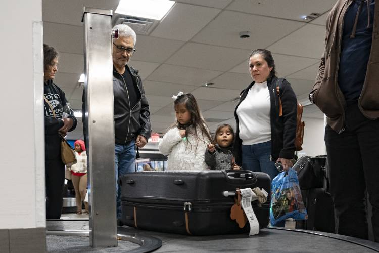 Airline passengers wait to retrieve their suitcases from a baggage claim carousel at LaGuardia Airport in New York, Tuesday, Nov. 21, 2023. (AP Photo/Peter K. Afriyie)