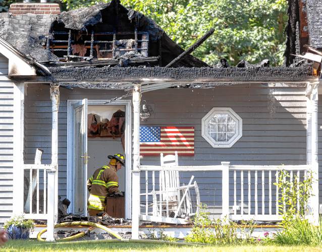 A firefighter sits in the entrance of the house on Elm Street in Concord after a fire gutted the middle of the dwelling on Saturday afternoon, July 13, 2024.
