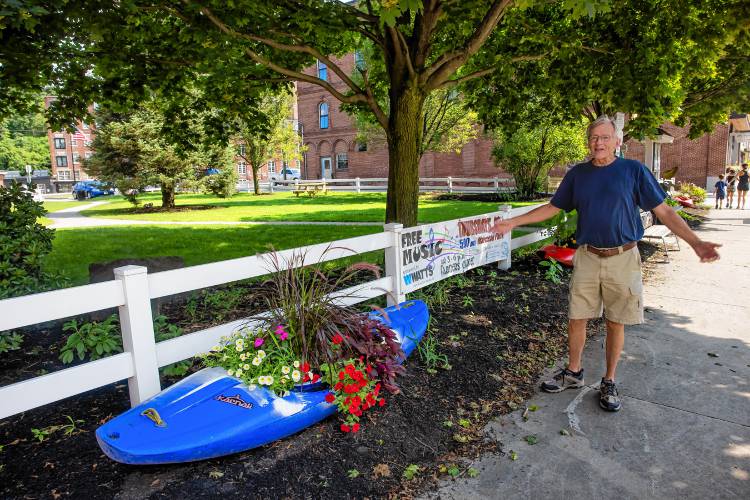 Glenn Morill stands along Central Street in Franklin, where kayaks adorn the street repurposed as flower beds. Morrill leads a team of volunteers behind the kayak flowerbeds each year.