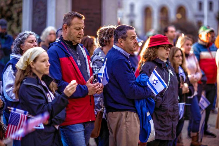The crowd holds candles along with the American and Israeli flags during a vigil at the State House in downtown Concord on Monday evening, October 7, 2024, on the anniversary of the Hamas attack on Israel.