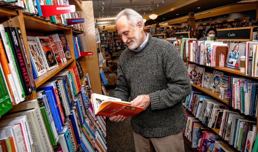 Michael Herrmann of Gibson's Bookstore looks at the store's cooking section selections on Wednesday, October 30, 2024. Hermann won 2024's New Hampshire Retailer of the Year.