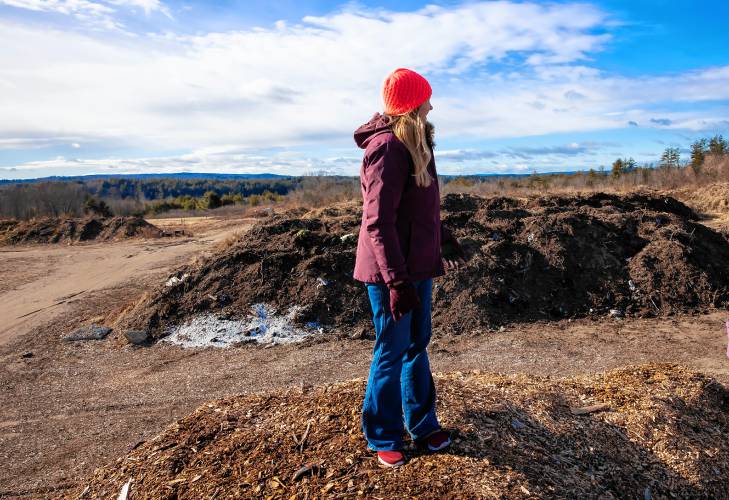 Rebecca McWilliams stands on a pile of woodchips overlooking the area where the family will be accepting food waste at Lewis Fam in Concord. Starting Feb. 1, James Meinecke and Rebecca McWilliams’ farm can accept food waste after New Hampshire’s new statewide food waste ban goes into effect. Lewis Farm is gearing up to handle an influx of commercial food scraps.