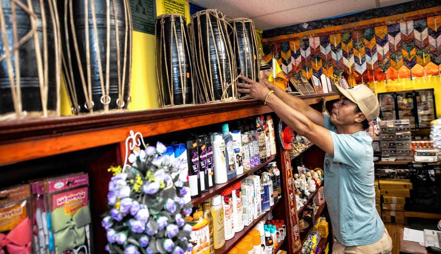 Karma Gonpo takes down drums from a top shelf; Gonpo has the shelves stocked with items that customers will find familiar from their native countries at the Katmandu Bazaar Market on Loudon Road in Concord.