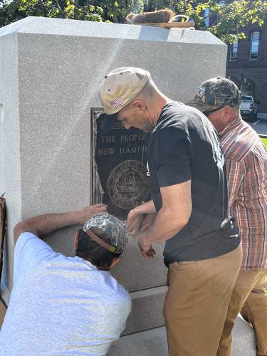 Workers put the plaque of Christa McAuliffe into place at the State House before the unveiling.