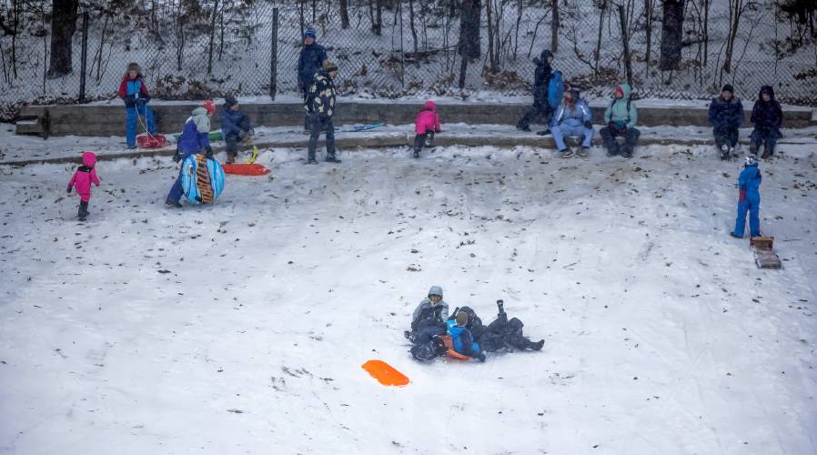 The snow hill at White Park was popular during the Sunday snowstorm for sledders and parents. Below: A dog jumps for joy in the snow at White Park during a walk with its owner on Sunday during the first snow of 2024.