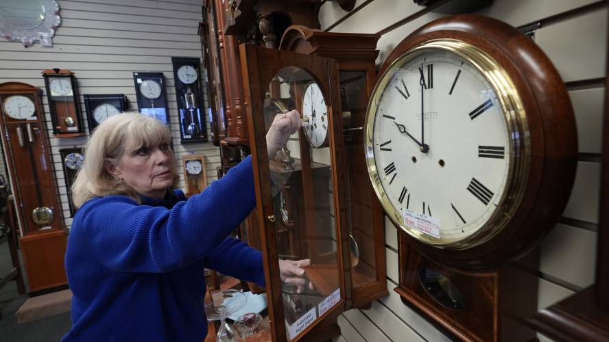 Glenda Marchesoni, owner of Heritage House Clocks, winds a clock at her shop Tuesday, March 5, 2024, in Farmers Branch, Texas. Once again, most Americans will set their clocks forward by one hour this weekend, losing perhaps a bit of sleep but gaining more glorious sunlight in the evenings as the days warm into summer. (AP Photo/LM Otero)
