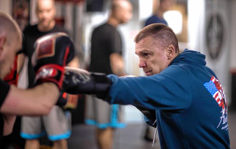 Coach Paul Averill shows his boxing class the proper technique at his boxing clinic in downtown Concord.