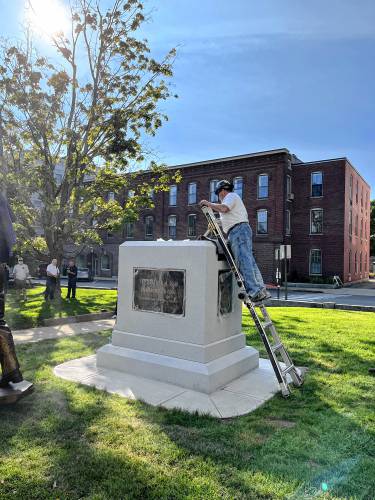 Workers get ready to place the statue Christa McAuliffe into place at the State House before the unveiling.