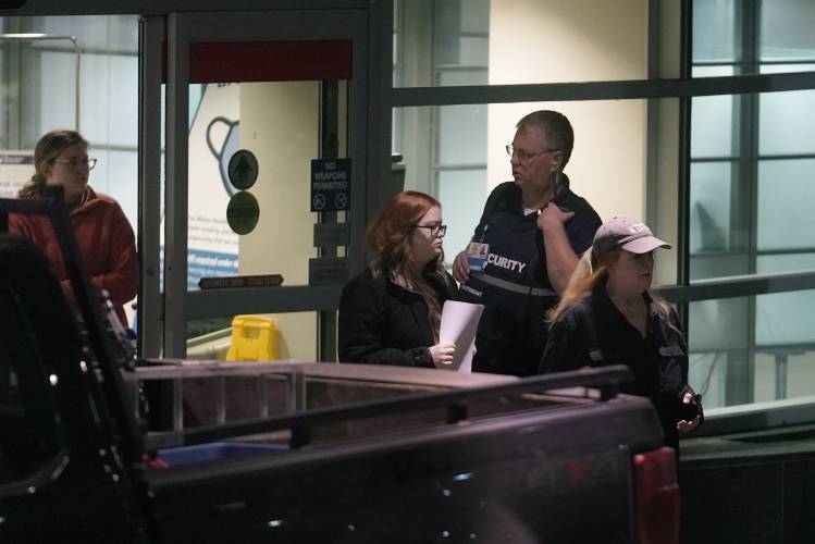 People depart an emergency department entrance at Central Maine Medical Center, past a member of security, behind right, during an active shooter situation, in Lewiston, Maine, Wednesday, Oct. 25, 2023. (AP Photo/Steven Senne)