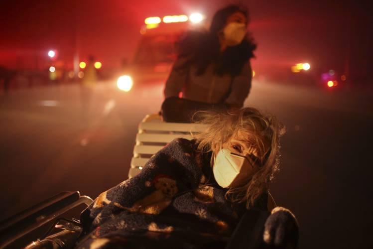 A resident of a senior center is evacuated as the Eaton Fire approaches Tuesday, Jan. 7, 2025 in Altadena, Calif. (AP Photo/Ethan Swope)