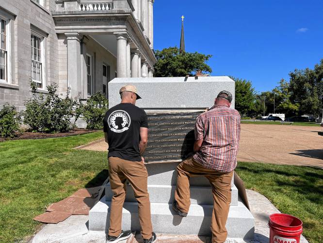Workers put the plaque of Christa McAuliffe into place at the State House before the unveiling.