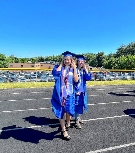 Olivia Worthen and Fiona Windsor hold on to their caps tightly as the wind blows at the John Stark Regional High School graduation ceremony on Saturday morning.