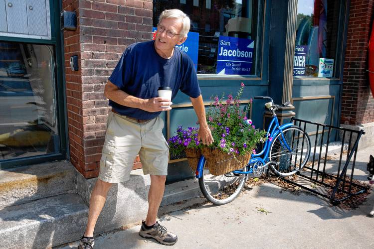 Glenn Morrill stands along Central Street in Franklin, where kayaks and bicycles adorn the street repurposed as flower beds. Morrill leads a team of volunteers behind the kayak flowerbeds each year.