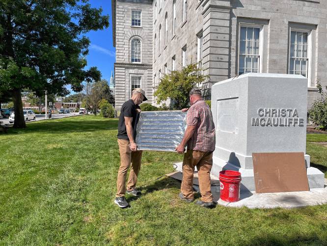 Workers put the plaque of Christa McAuliffe into place at the State House before the unveiling.