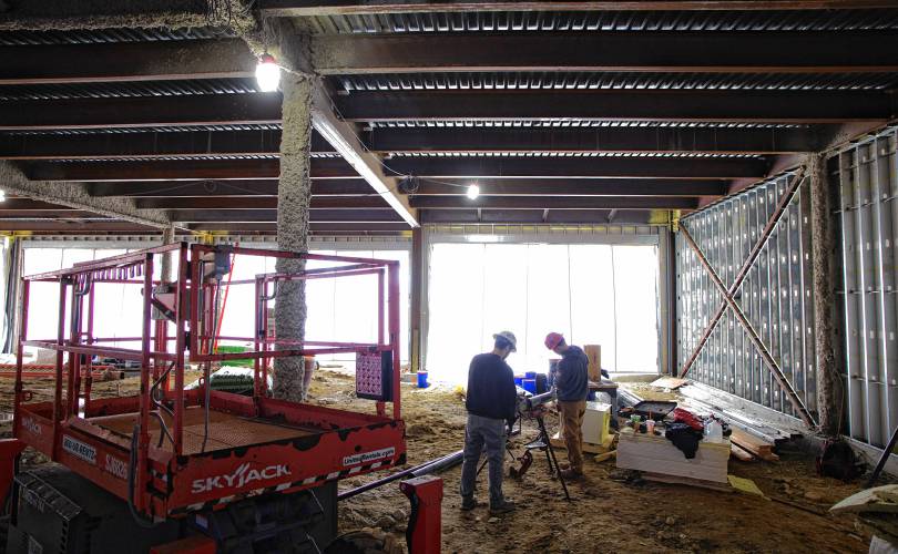 The construction of the Friendly Toast and Arts Alley in downtown Concord is taking shape. Workers inside the structure cut aluminum for the first floor siding.