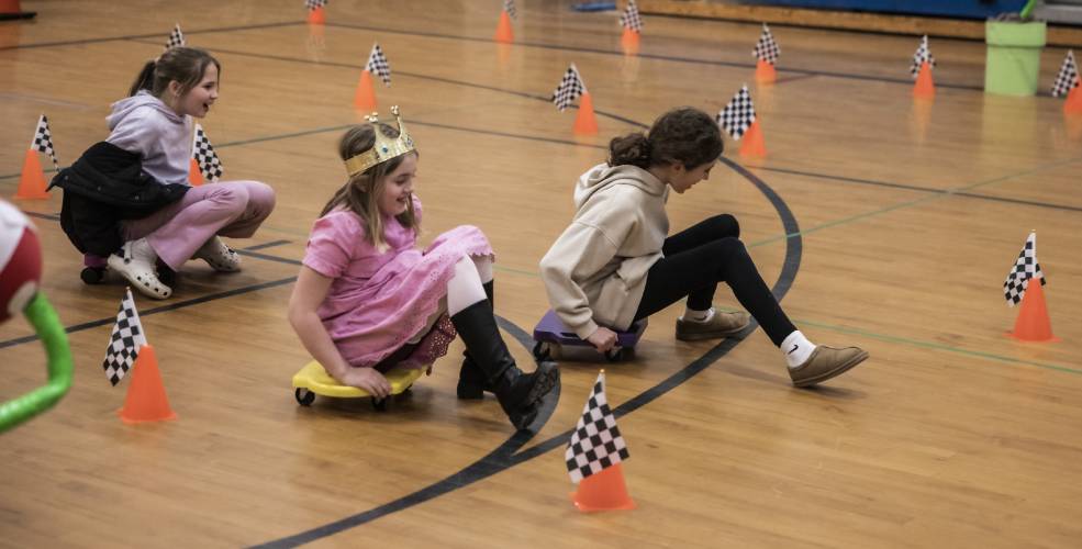 Molly Rudis (right) and sisters Sophie and Caitlyn Kleiner run in the Mario cart race in the Penacook Elementary School gym during the Escape Room family engagement night at the school on Thursday, March 27, 2025.