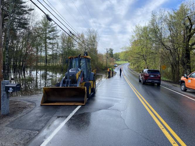 Dunbarton Chief Chris Remillard directs traffic around a flooded portion of Route 13 near the center of town Wednesady, may 7, 2025. Beavers had plugged up a culvert under the road after days of heavy rain. State Department of Transportation workers cleared it.