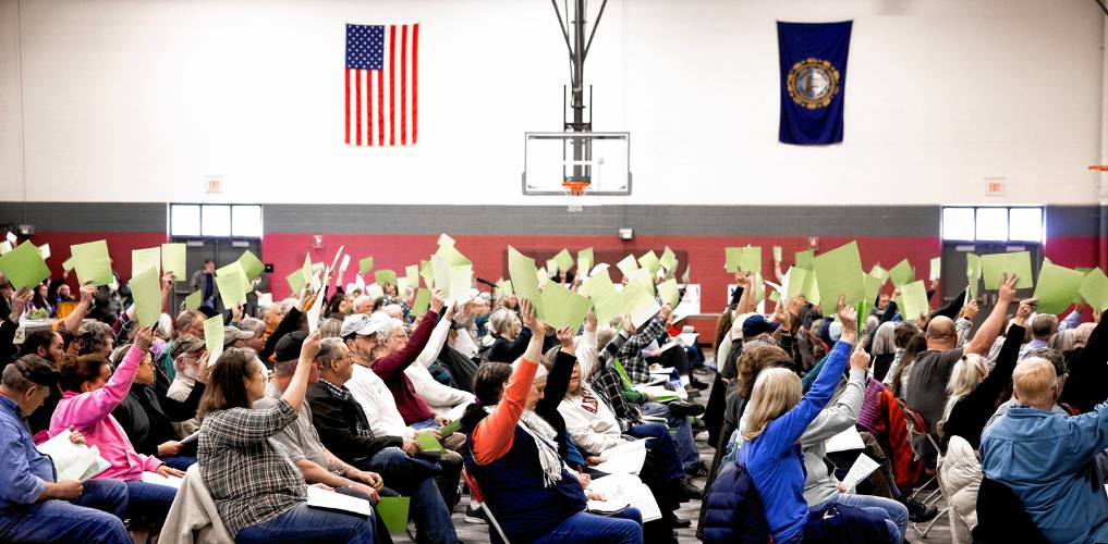 Loudon residents raise their cards to pass an article at the town meeting on Saturday, March 16, 2024.