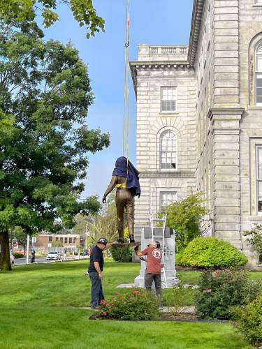 Workers put the statue of Christa McAuliffe into place at the State House before the unveiling.