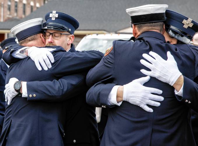 Concord firefighter Justin Kantar (left) gets a hug from a fellow firefighters after the service for CJ Girard at Christ the King Catholic Church.