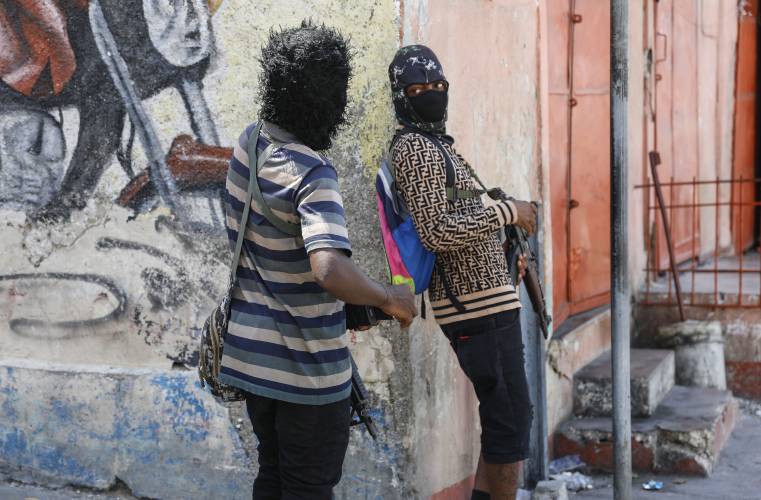 Members of the G9 and Family gang speak to each other while standing guard at their roadblock in the Delmas 6 neighborhood of Port-au-Prince, Haiti, Monday, March 11, 2024. (AP Photo/Odelyn Joseph)