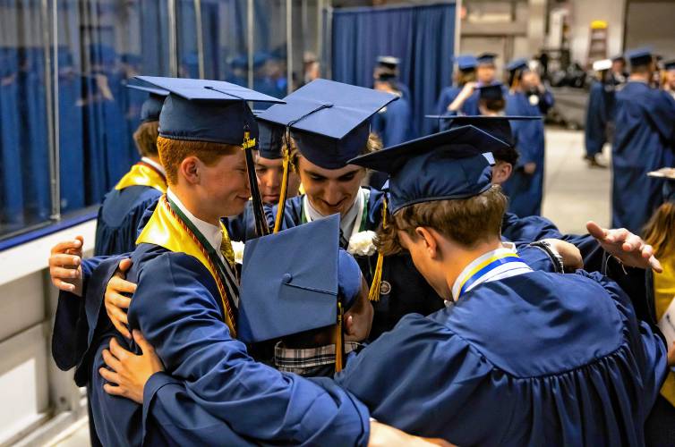 Borthers Shannon McGrade and brother, Ryan (center) get a group hug from their friends as they line up to process into the stage of the Sullivan Arena at St. Anselm College, ready to graduate with the Bow High School class of 2024.