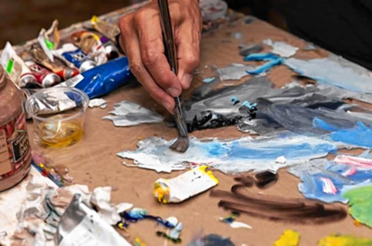 Artist Jay Mercado mixes his oil paints to create a cool blue-gray color, to accentuate and texturize the stone border on a large fruit still life, in his studio at his home in Jaffrey on Tuesday afternoon.