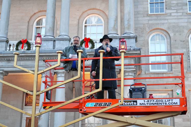 Rabbi Levi Krinsky, regional director of Chabad of New Hampshire and Scott Plaut of Nashua, kindle the 13-foot Menorah in front of the State House marking the first night of Hanukkah. Hanukkah is celebrated for eight days with an additional candle lit each night.